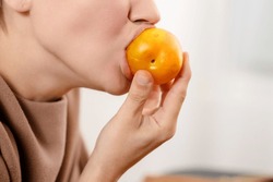 Healthy snack: An attractive woman bites into a plump, yellow plum, relishing the health benefits of her fruity snack