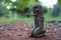 Taino Antique Stone Idol Figure sitting on the ground with folded legs. Taino Indian Mythology.
