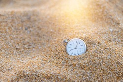 Vintage watch on sand beach with vintage morning warm light, swimming in the time, loosing time, sand watch, outdoor day light