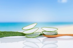 Aloe vera slices on wooden spoon over blurred beach background, fresh organic aloe vera for healthy skin