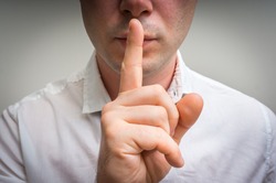 Attractive man with finger on lips making silence gesture. Shh!!!