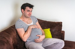 Funny image of pregnant man with pregnant belly at home