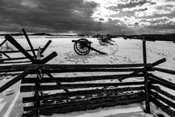 A black and white photo of Civil War cannons in the snow at the Gettysburg National Military Park on the field of Pickett's Charge.