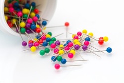 Multi colour map push pin needles fall out from white jar isolated white background.