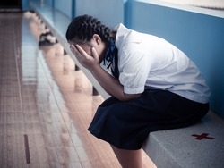 Asian young girl student sitting alone with sad feeling at school