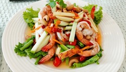 Spicy Thai mixed seafood salad, famous is thai food on the white plate in the restaurant.