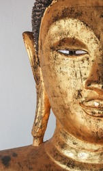 Closeup of the face of buddha's image covering with gold leaf.