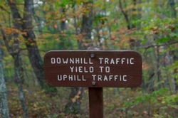 Outdoor carved wood sign that says DOWNHILL TRAFFIC YIELD TO UPHILL TRAFFIC