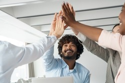 Diverse multi-ethnic business team bonding and success, teamwork and unity. Happy people excited creative group raising hands up giving high five together celebrating winning and triumph