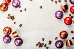 Espresso coffee capsules or pods and coffee beans on grey background, top view