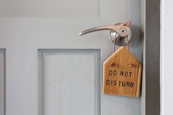 The wooden sign says do not disturb hanging on the door.