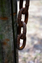 old rusty chain hanging from wooden post