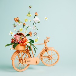 Retro orange bicycle with flowers flying out of basket against pastel green background. Creative flower delivery concept. Florist or spring bloom banner with copy space. Natural romantic card.