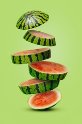 Summer fruit arrangement with slices of watermelon falling down stacked on a light green background. Creative food concept. Abstract composition.