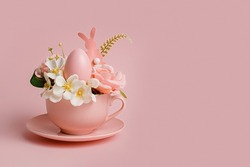 Easter egg and spring flowers in tea cup on bright pink background. Creative Easter holiday concept. Minimal greeting card with copy space for text.