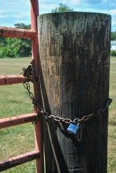 Chain and Lock on Rustic Wooden Post and Rusty Metal Gate 