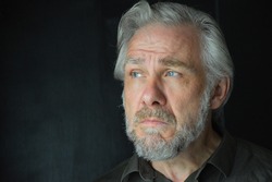 Grey haired man with beard looking to one side