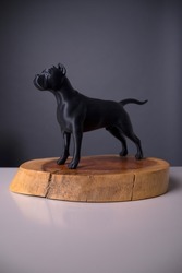 
3D all-black guard dog figure made in plastic on a wooden base. Studio photo of breed dog model mockup.