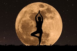 Silhouette young woman with good shape practicing yoga under full moon at night with stars