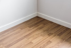 Laminated wood floor with white wall, room's corner