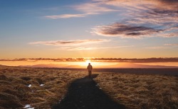 a man walking alone on footpath, Landscaped of Iceland, at Hvitserkur in Sunset