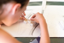 Young girl learning on the course of architectural design for children - preparing architectural model
