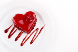 Heart shaped red velvet cake decorated with red currant on white plate, overhead view
