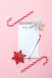 Christmas or new year wish list, pen and wooden ornaments on pink background, festive decorations, vertical 