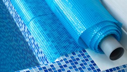 Blue tarpaulin pool cover. Bubble awning wrap for swimming pool cover. Swimming pool with a blue water.