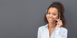 Call center worker isolated on a gray background. Smiling customer support operator at work. Young employee working with a headset.