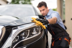 Car detailing - the man holds the microfiber in hand and polishes the car. Selective focus.