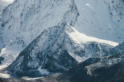 Awesome mountain landscape with big snow rock with peaked top on background of giant snow-covered mountain wall in sunshine. Atmospheric scenery with snowy mountains in sunlight. Great snowy mountains