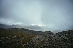 Dark atmospheric landscape on edge of abyss in highlands. Dangerous mountains and abyss among low clouds. Danger mountain pass and sharp rocks in clouds. Dangerous cloudy rainy weather in mountains.