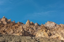 Scenic mountain landscape with sharp rocks under blue sky in sunny day. Colorful scenery with gold sunlit sharp rocky mountains. Sharp rocks in bright sun. High rocky mountains in golden sunlight.