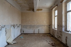 Empty old room in an abandoned building. Window light is shining in. Paint is peeling off the walls before renovation. Construction site of an ancient house can be used as abstract background picture.