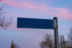 Blank road sign on a post. Template for the name of a street in front of an evening sky. Mockup of a metal plate showing information for traffic in Germany.