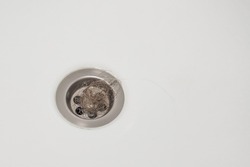 Clogged bathroom drain due to loose hair. A bundle of hair obstructing the drain. The problem of hair loss