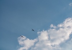 Glider near clouds. Small plane pulls glider to the sky to start the gliding flight. Thy sky is blue with some clouds. 