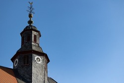 Church clock. Close up church tower with roff shingles. Ancient clock and old white, black and golden clock-face. Sunny day with blue sky and few clouds.