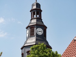 Close up church tower with clock. ancient clock with old clock-face. Sunny day with blue sky and few clouds.