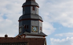 Close up church tower with clock. Ancient clock with blue and golden shiny clock-face. Sunny day with blue sky and few clouds.