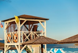 Lifeguards look through binoculars on the observation tower on the beach against the blue sky.