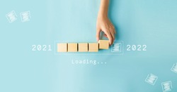 Hand of woman putting wood cube countdown to 2022. Loading year 2021 to 2022.