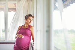 Pregnant woman near the window at home