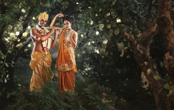 Krishna and Radha in the forest. Full length of Hindu God Krishna playing flute to his beloved Radha