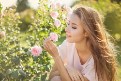 Beautiful young woman smelling a rose flower