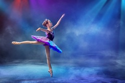 little Japanese ballerina dances on stage in a lilac tutu on pointe shoes classical ballet.