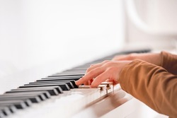 Selective focus to kid fingers and piano key to play the piano. There are musical instrument for concert or learning music. Close up hand of child musician playing the piano on stage.
