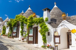 Beautiful town of Alberobello with trulli houses among green plants and flowers, main touristic district, Apulia region, Southern Italy