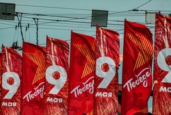 several red holiday flags fluttering in the wind in a row with the inscriptions May 9 and Victory! on victory day